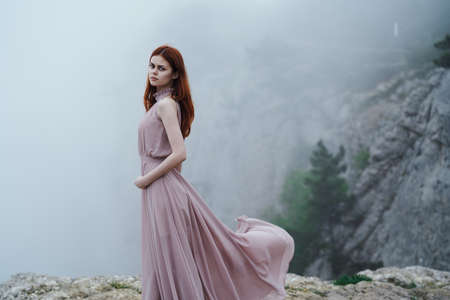 Beautiful young woman in a long dress in the mountains.の写真素材
