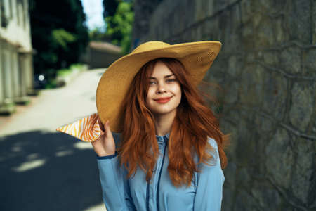 Beautiful young woman in a hat walking along a street in the city.の写真素材