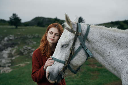 Young beautiful woman holds a horse, nature, mountains, hills.の写真素材