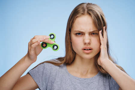 Young woman on a blue background holds a spinner.