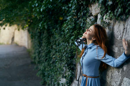 Young beautiful woman is walking outdoors with a camera.の写真素材