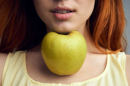 Beautiful young woman on a gray background holding an apple.