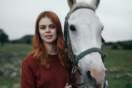 Beautiful young woman on nature in the mountains walking with horse.
