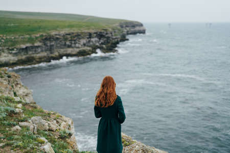 Beautiful young woman on a cliff above the sea, nature.の写真素材