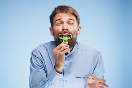 A young guy with a beard on a blue background holds a spinner.の写真素材