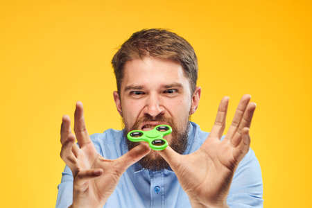 A young guy with a beard on a yellow background holds a spinner.の写真素材