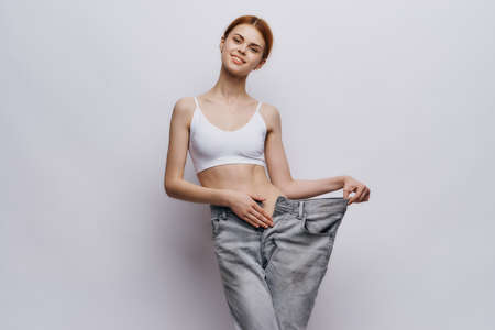 Beautiful young woman on a light background, losing weight, diet, progress, success.の写真素材