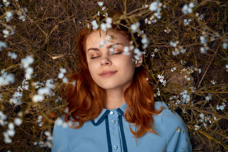 Beautiful young woman lies in flowers in a field.の写真素材