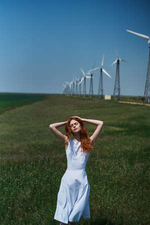 Beautiful young woman in a field near a windmill, summer, sun.の写真素材
