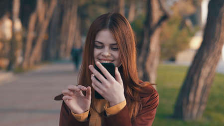 Beautiful young woman looking into the phone in the park.の写真素材