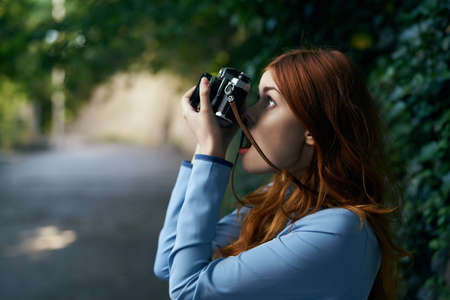Beautiful young woman walking along a city street with a camera.の写真素材
