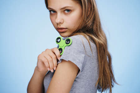 Beautiful young woman on a blue background holds a spinner.の写真素材