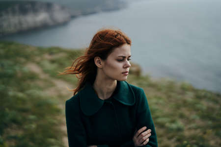 Beautiful young woman standing on a cliff of a mountain over the sea.の写真素材