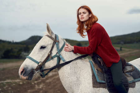 Beautiful young woman in the mountains walking with her horse.