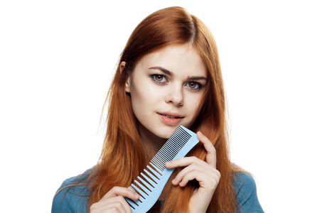 Beautiful young woman on white isolated background holds a comb.