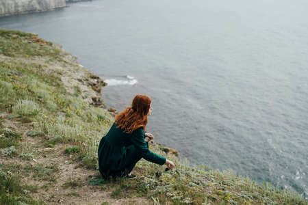 beautiful young woman on the precipice of a mountain near the sea.の写真素材