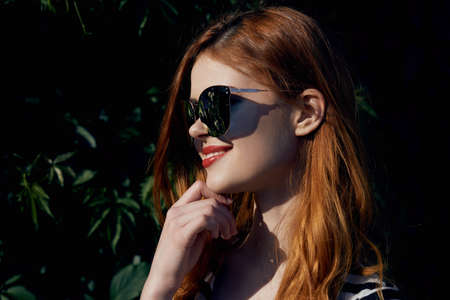 Beautiful young woman in sunglasses walking along the street.の写真素材