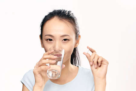 Beautiful young woman on white isolated background, drink pill, asian.の写真素材
