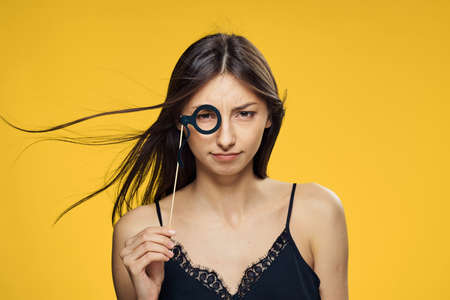 Beautiful young woman on a yellow background holds a paper accessory for parties.