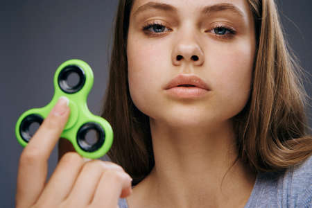 Beautiful young woman on a gray background holds a spinner.