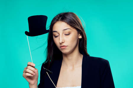 Beautiful young woman on a green-blue background holds paper accessories for parties.の写真素材