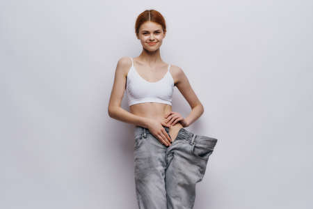 Beautiful young woman on a light background, leanness, diet, weight loss, success, progress.の写真素材