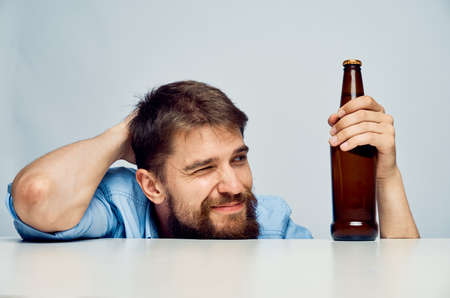 Young guy with a beard on a white isolated background holds a bottle of beer, alcohol.の写真素材