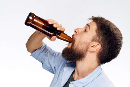 Young guy with a beard on a white isolated background holds a bottle of beer, alcohol.の写真素材