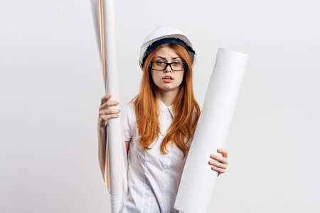 Young beautiful female engineer holding blueprints on white isolated background.の写真素材