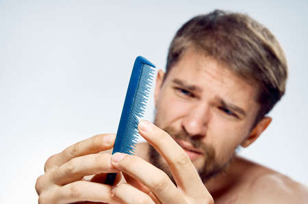 Young guy with a beard on a white isolated background holds a comb.の写真素材