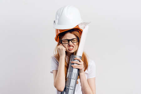 Young beautiful female engineer holding blueprints on white isolated background.の写真素材
