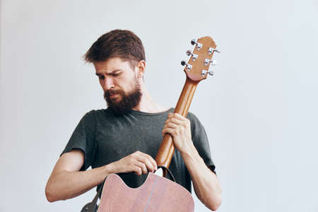 Young guy with a beard on a white isolated background playing a guitar.