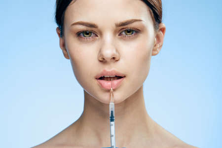 Young beautiful woman on a blue background holds a syringe, medicine, nurse.の写真素材