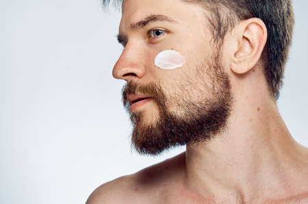 Young guy with beard on white isolated background, face cream.の写真素材