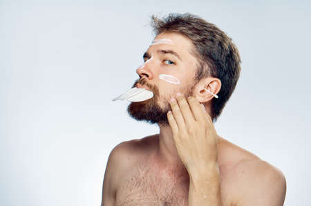 Young guy on white isolated background, cream, cotton pads, ear wand.