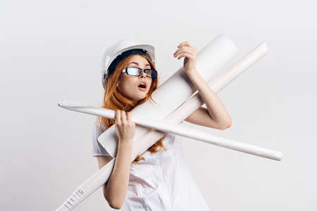 Beautiful young woman engineer on white isolated background holds blueprints.の写真素材