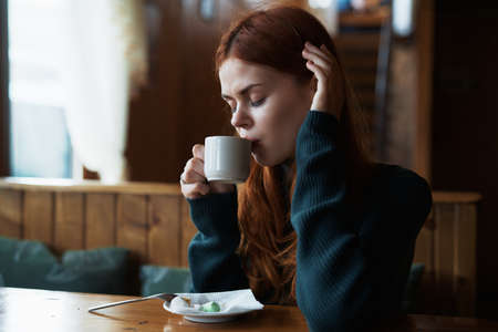 Beautiful young woman drinks coffee in a cafe.の写真素材