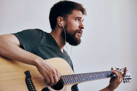 Young guy with a beard on a white isolated background playing a guitar.