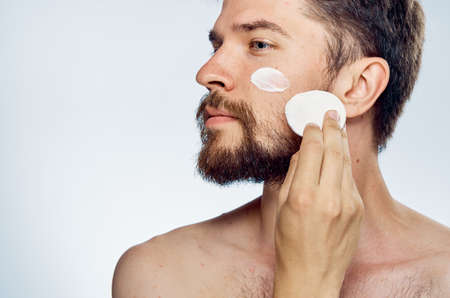 Young guy with beard on white isolated background, cream.の写真素材