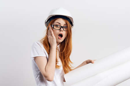 Beautiful young woman engineer on white isolated background holds blueprints.の写真素材