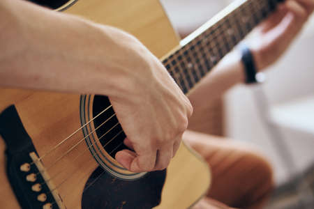 Young guy with a beard on a light background playing the guitar.