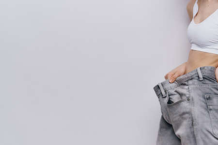 Beautiful young woman on a light background, losing weight, diet, loss of kilograms.の写真素材