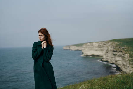 Beautiful young woman on a cliff of a mountain near the sea.の写真素材