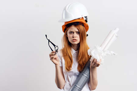 Beautiful young woman engineer on white isolated background holds blueprints.の写真素材
