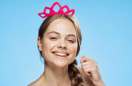 Beautiful young woman on a blue background holds paper accessories for parties.の写真素材