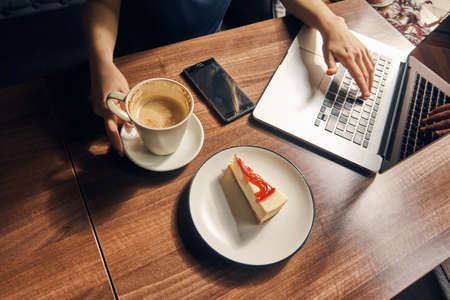 Beautiful young woman working behind laptop in cafe.の写真素材