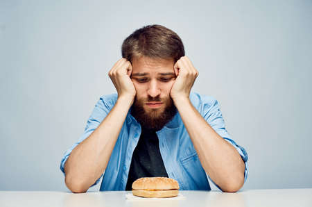 Young guy with a beard on a light background, a hamburger, fast food.の写真素材