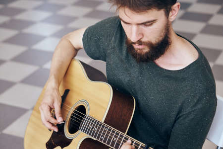 Young guy with a beard playing the guitar.の写真素材