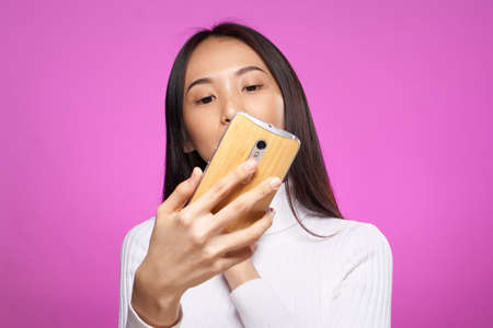 Beautiful young woman on a pink background doing selfie, asian.の写真素材