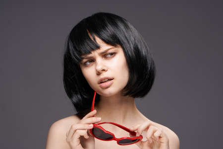 Beautiful young woman on a dark background with glasses-hearts.